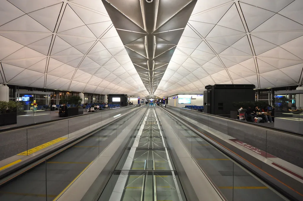 Travellers crossing a wide, bright arrivals hall at an Asian international airport.